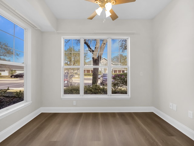 empty room featuring a ceiling fan, baseboards, and dark wood finished floors