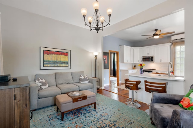 living room featuring ceiling fan with notable chandelier, hardwood / wood-style flooring, a wall mounted AC, and sink