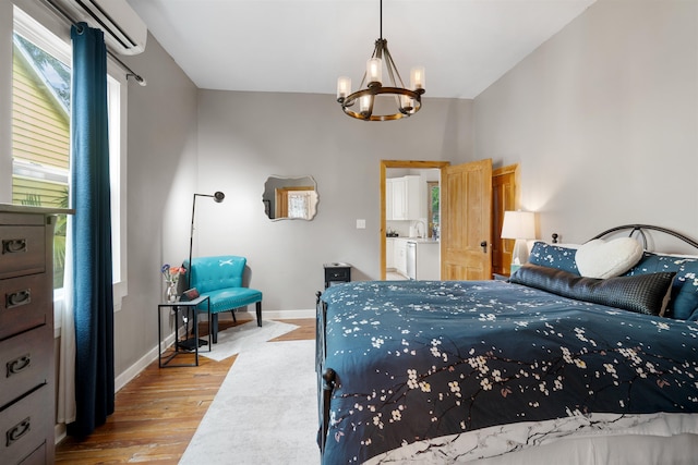 bedroom featuring an AC wall unit, light hardwood / wood-style flooring, and a notable chandelier