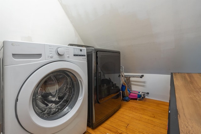 washroom with hardwood / wood-style flooring and washing machine and dryer