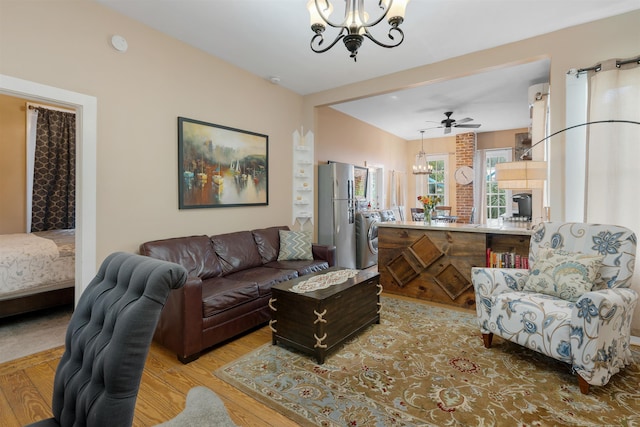 living room featuring ceiling fan with notable chandelier and light hardwood / wood-style flooring