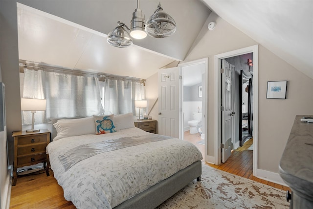 bedroom with ensuite bath, vaulted ceiling, a spacious closet, light wood-type flooring, and a closet