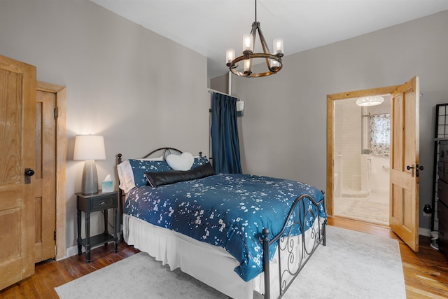 bedroom with hardwood / wood-style floors, connected bathroom, and an inviting chandelier