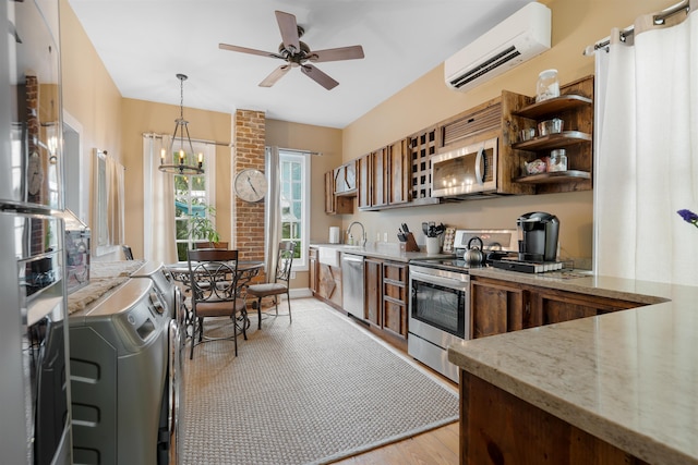 kitchen with washer / clothes dryer, appliances with stainless steel finishes, decorative light fixtures, light hardwood / wood-style floors, and a wall unit AC