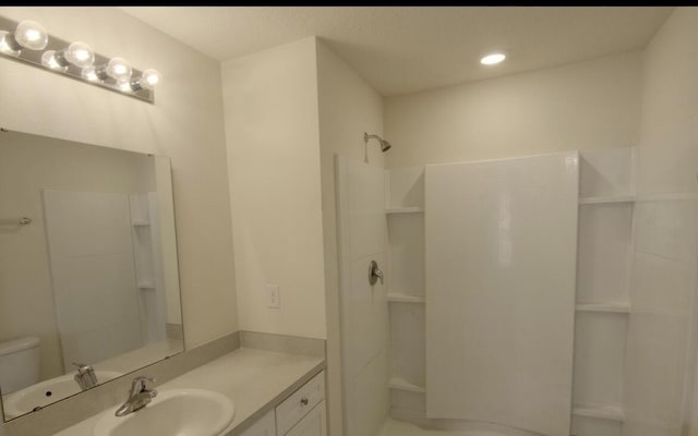 bathroom featuring vanity, a shower, and toilet