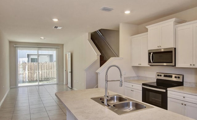 kitchen with range with electric stovetop, sink, light tile patterned floors, and white cabinets