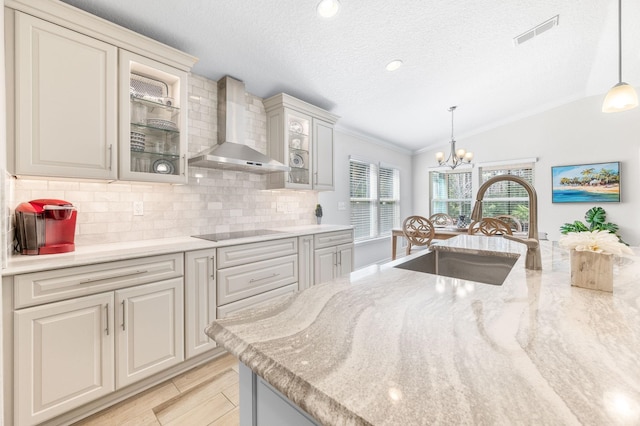 kitchen featuring an inviting chandelier, lofted ceiling, a sink, wall chimney range hood, and black electric cooktop