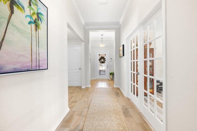 corridor featuring visible vents, baseboards, crown molding, and light wood-style floors