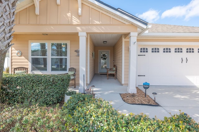 entrance to property featuring a porch, concrete driveway, a garage, and board and batten siding