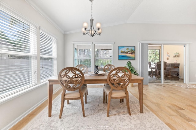 dining space with a wealth of natural light, light wood-type flooring, an inviting chandelier, and vaulted ceiling