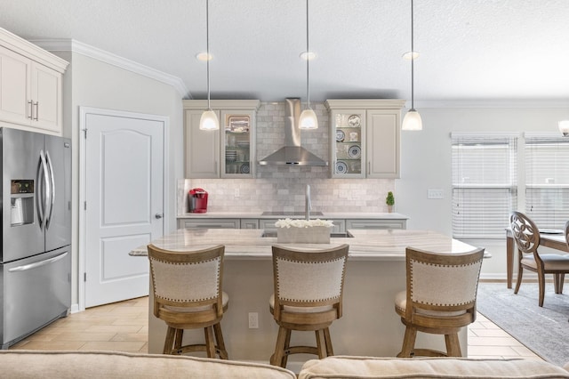 kitchen featuring stainless steel fridge, tasteful backsplash, light countertops, and wall chimney range hood