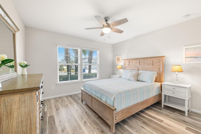 bedroom featuring light wood-style flooring, a ceiling fan, and baseboards