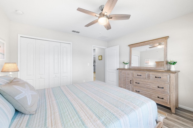 bedroom with light wood-type flooring, visible vents, a closet, and a ceiling fan