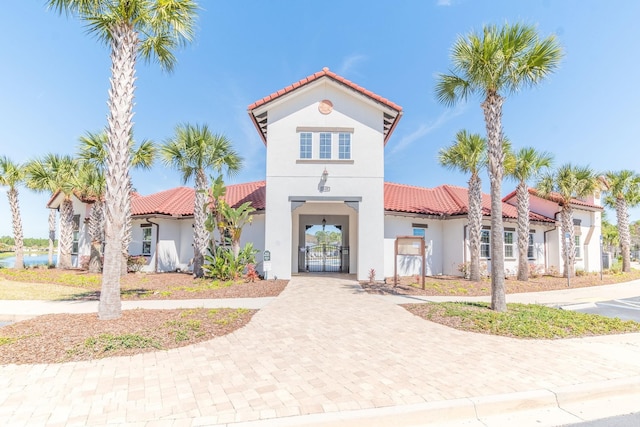 mediterranean / spanish-style home featuring a gate, stucco siding, and a tiled roof