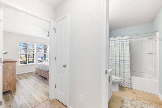 full bathroom featuring vanity, a ceiling fan, shower / bathtub combination with curtain, wood finished floors, and toilet