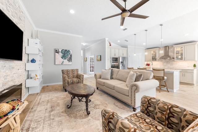 living room with baseboards, light wood-style flooring, a ceiling fan, and crown molding