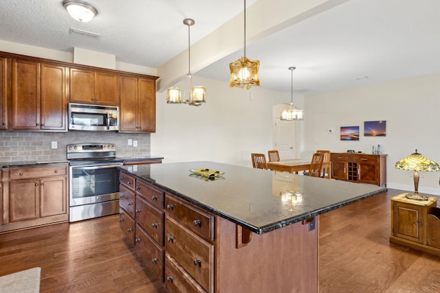 kitchen featuring tasteful backsplash, visible vents, stainless steel appliances, and dark wood finished floors