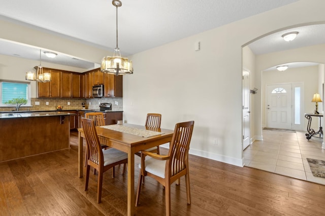 dining space with arched walkways, dark wood-style flooring, and baseboards