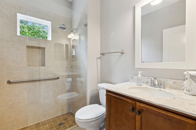 bathroom with tiled shower, vanity, and toilet