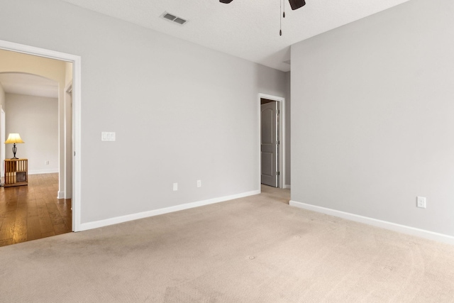 unfurnished room with baseboards, visible vents, arched walkways, a ceiling fan, and carpet floors