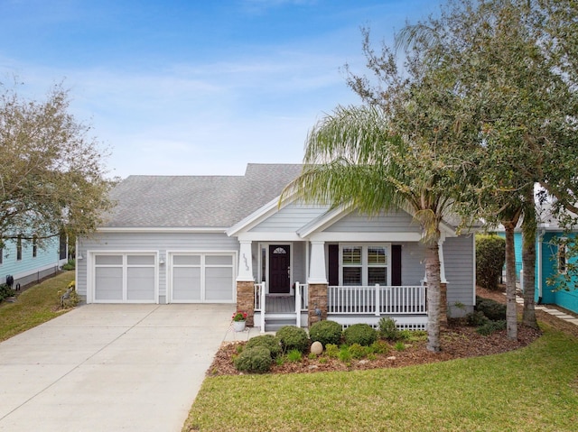 craftsman-style home with driveway, covered porch, and a front lawn