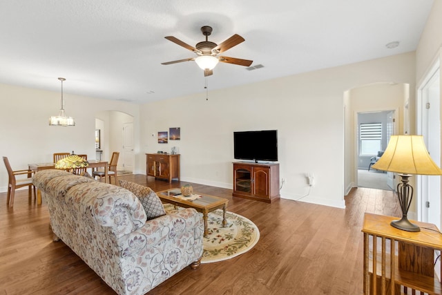 living room with baseboards, visible vents, arched walkways, and wood finished floors