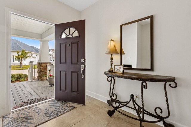 foyer entrance with light tile patterned floors and baseboards