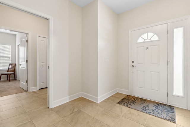 foyer entrance with light tile patterned flooring and baseboards