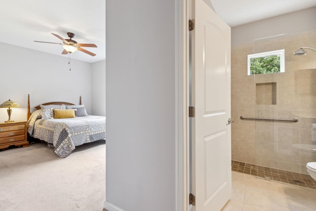 carpeted bedroom with tile patterned flooring, connected bathroom, and ceiling fan