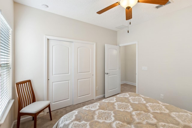 bedroom featuring a textured ceiling, light colored carpet, a ceiling fan, visible vents, and a closet