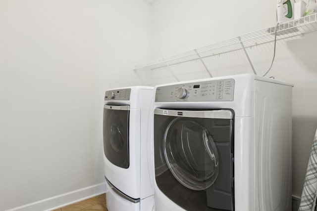 laundry room with laundry area, light tile patterned floors, baseboards, and washer and clothes dryer