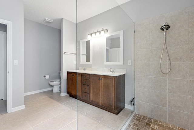 bathroom featuring tile patterned flooring, toilet, a sink, tiled shower, and double vanity