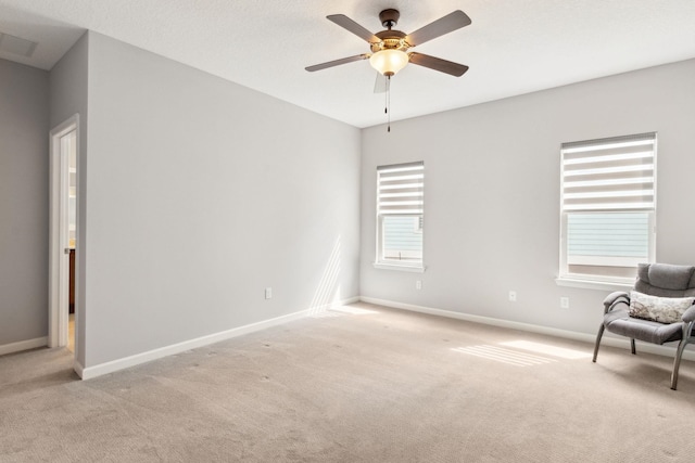 unfurnished room featuring a ceiling fan, light colored carpet, visible vents, and baseboards