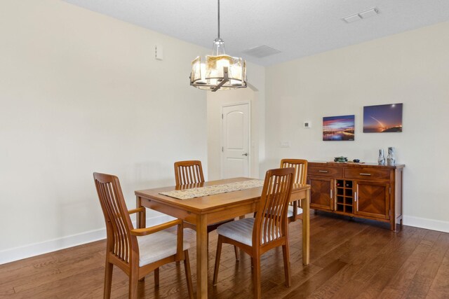 dining area featuring an inviting chandelier, visible vents, baseboards, and dark wood finished floors