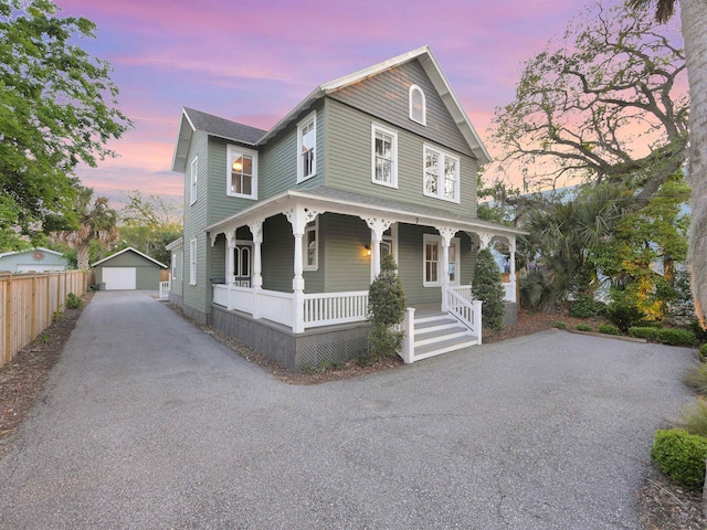 view of front of house featuring a garage, a porch, and an outbuilding