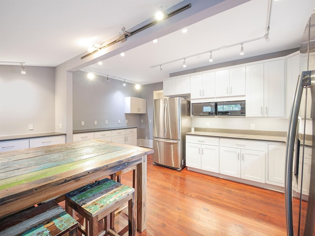 kitchen featuring white cabinetry, track lighting, stainless steel fridge, and light hardwood / wood-style flooring