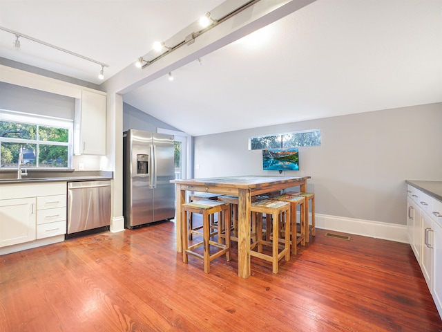 kitchen with stainless steel appliances, white cabinetry, sink, and light wood-type flooring