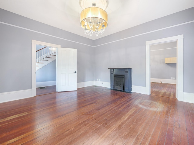 unfurnished living room featuring hardwood / wood-style flooring and a chandelier