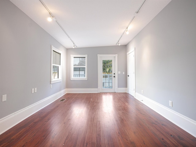 spare room featuring rail lighting and wood-type flooring