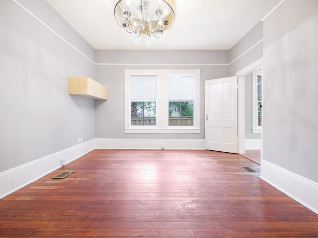 empty room with wood-type flooring and a chandelier