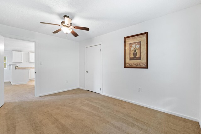 carpeted spare room featuring ceiling fan and a textured ceiling