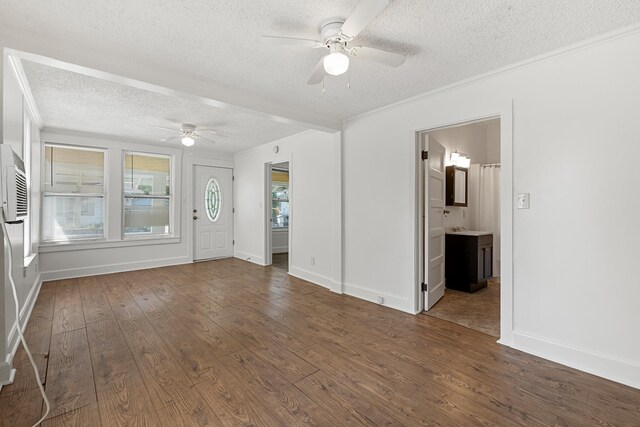 interior space featuring a textured ceiling, ceiling fan, ornamental molding, and dark wood-type flooring