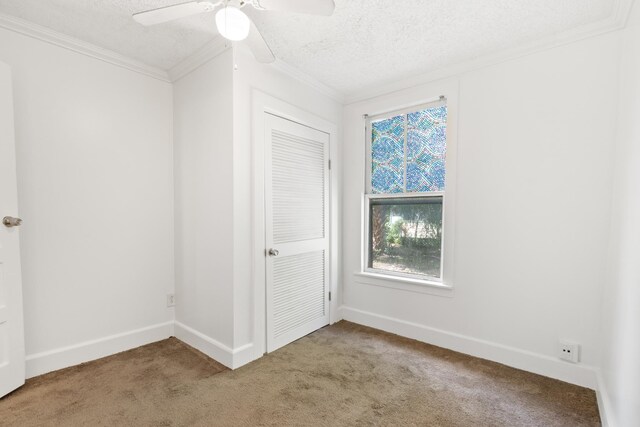 carpeted spare room with ceiling fan, a textured ceiling, and ornamental molding