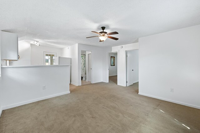 empty room with a textured ceiling, ceiling fan, and light carpet