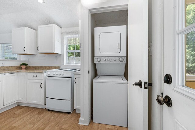 laundry area with a textured ceiling, light hardwood / wood-style flooring, and stacked washer / dryer