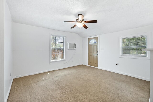 spare room featuring carpet, a textured ceiling, a wall mounted air conditioner, and ceiling fan