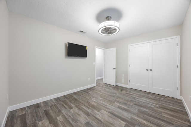 unfurnished bedroom featuring a textured ceiling, hardwood / wood-style flooring, and a closet