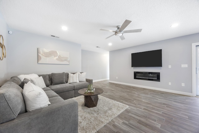 living room with ceiling fan, a textured ceiling, and hardwood / wood-style flooring