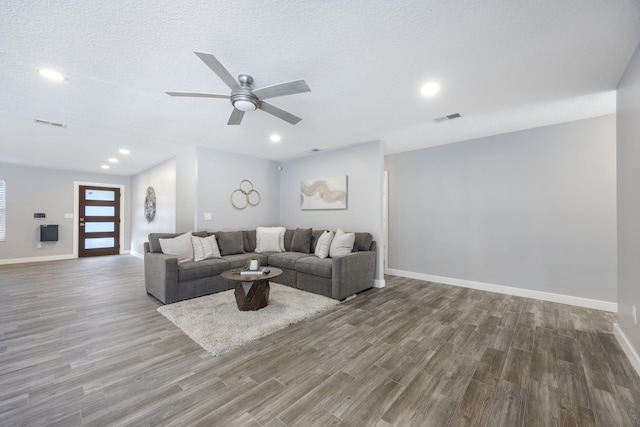 living room featuring ceiling fan, hardwood / wood-style floors, and a textured ceiling