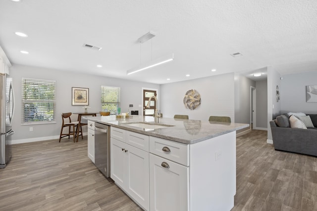 kitchen with sink, light wood-type flooring, a center island with sink, white cabinets, and appliances with stainless steel finishes